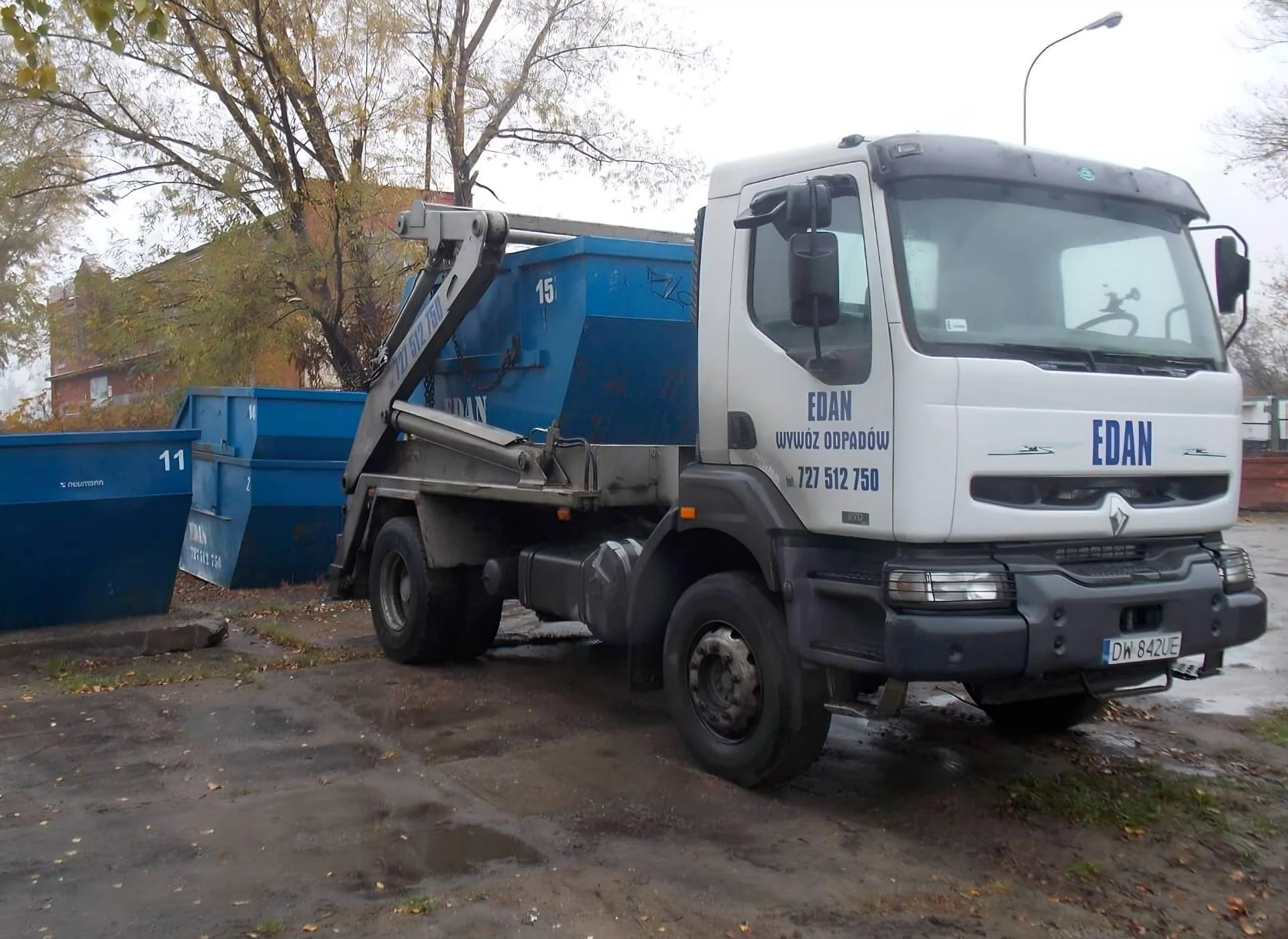 Samochód ciężarowy z niebieskim kontenerem na gruz